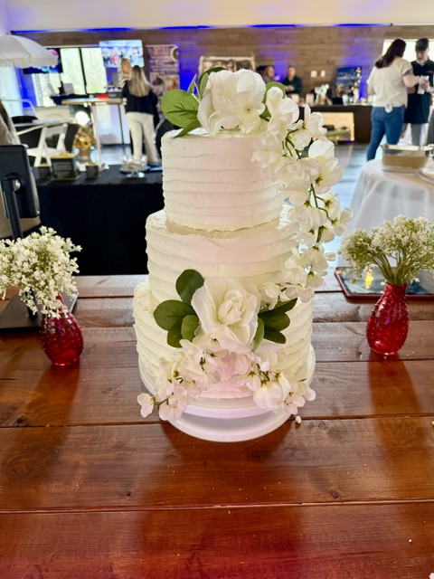 Three-tier white wedding cake with fresh florals